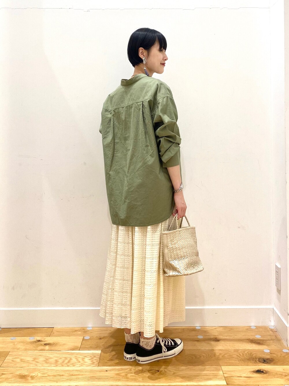 グリーン系のシャツ/ブラウス、ホワイト系のスカート、ブラック系のスニーカーを着用したレディースの春コーディネートの3枚目の写真