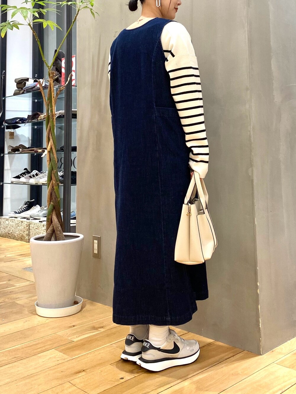 ホワイト系のニット/セーター、ブルー系のジャンパースカート、ホワイト系のトートバッグを着用したレディースの冬コーディネートの4枚目の写真