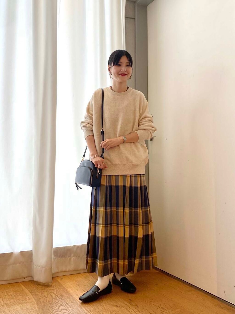 ブラック系のローファー、ブラック系のショルダーバッグ、ブルー系のスカートを着用したレディースの秋コーディネートの3枚目の写真