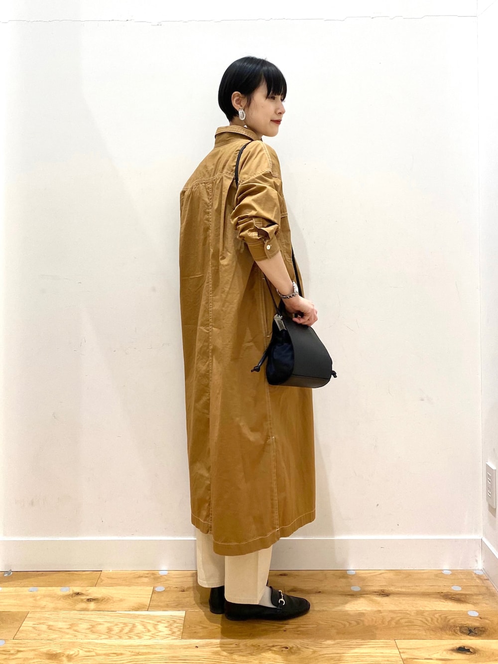 イエロー系のワンピース、ベージュ系のデニムパンツ、ブラック系のショルダーバッグを着用したレディースの春コーディネートの4枚目の写真