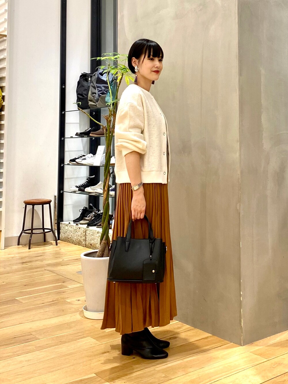 ホワイト系のカーディガン/ボレロ、ブラック系のタンクトップ、イエロー系のスカートを着用したレディースの秋コーディネートの3枚目の写真