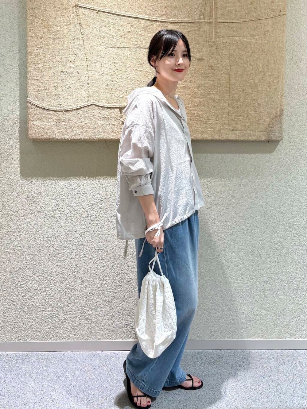 ブルー系のデニムパンツ、ホワイト系のショルダーバッグ、グレー系のシャツ/ブラウスを着用したレディースの夏コーディネートの2枚目の写真