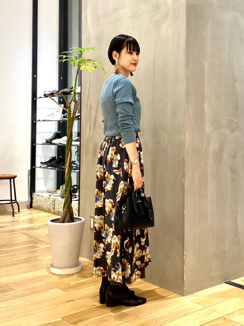 ブルー系のTシャツ/カットソー、グレー系のスカート、ブラック系のトートバッグを着用したレディースの秋コーディネートの3枚目の写真