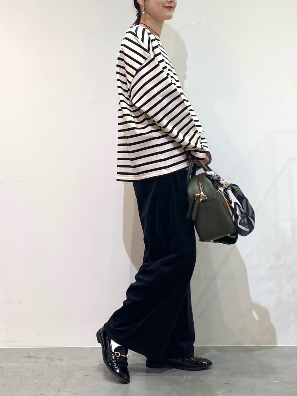 ホワイト系のTシャツ/カットソー、ブラック系のその他パンツ、グリーン系のボストンバッグを着用したレディースの秋コーディネートの4枚目の写真