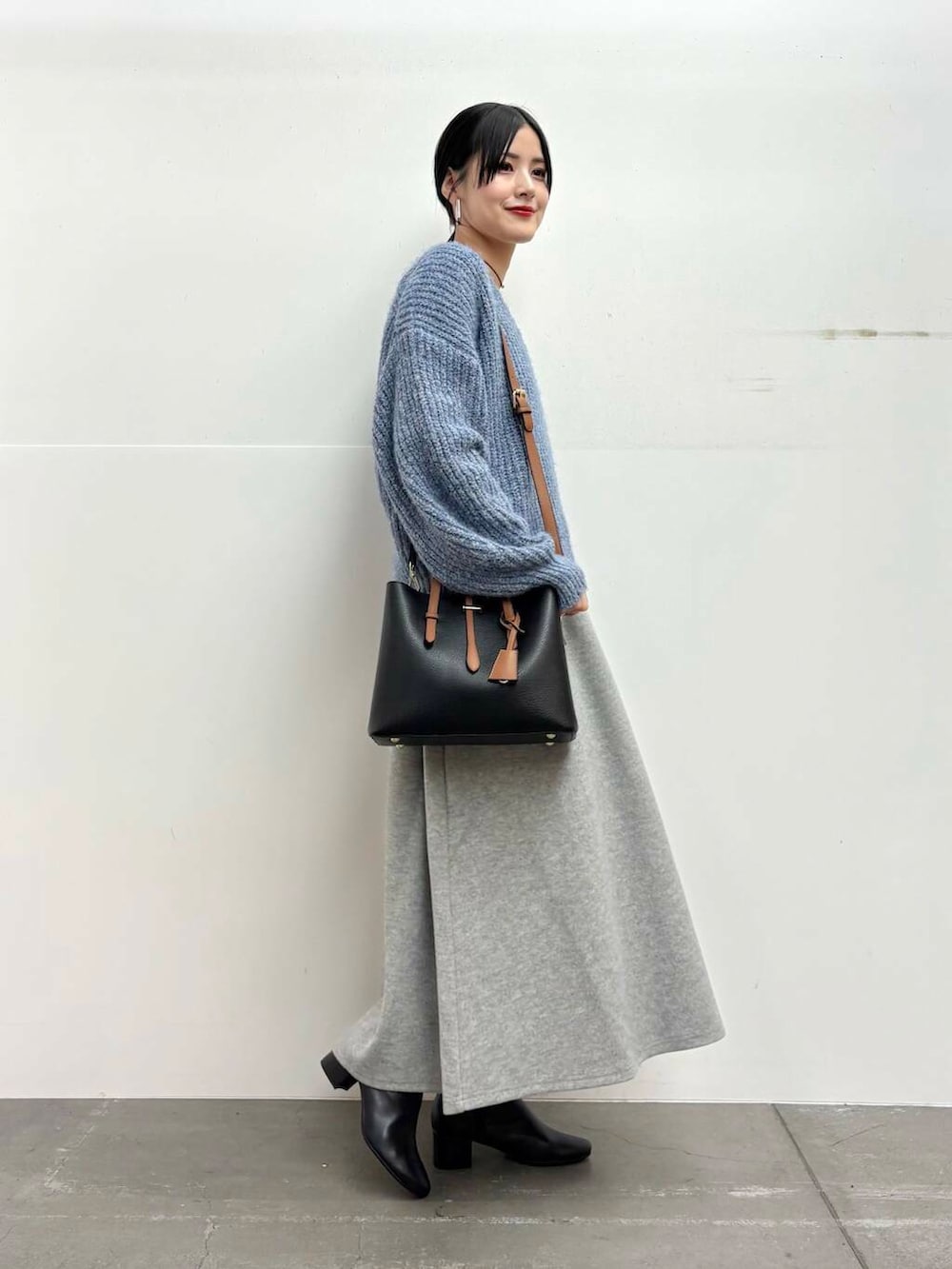 ブラック系のブーツ、ブラック系のトートバッグ、グレー系のスカートを着用したレディースの冬コーディネートの2枚目の写真