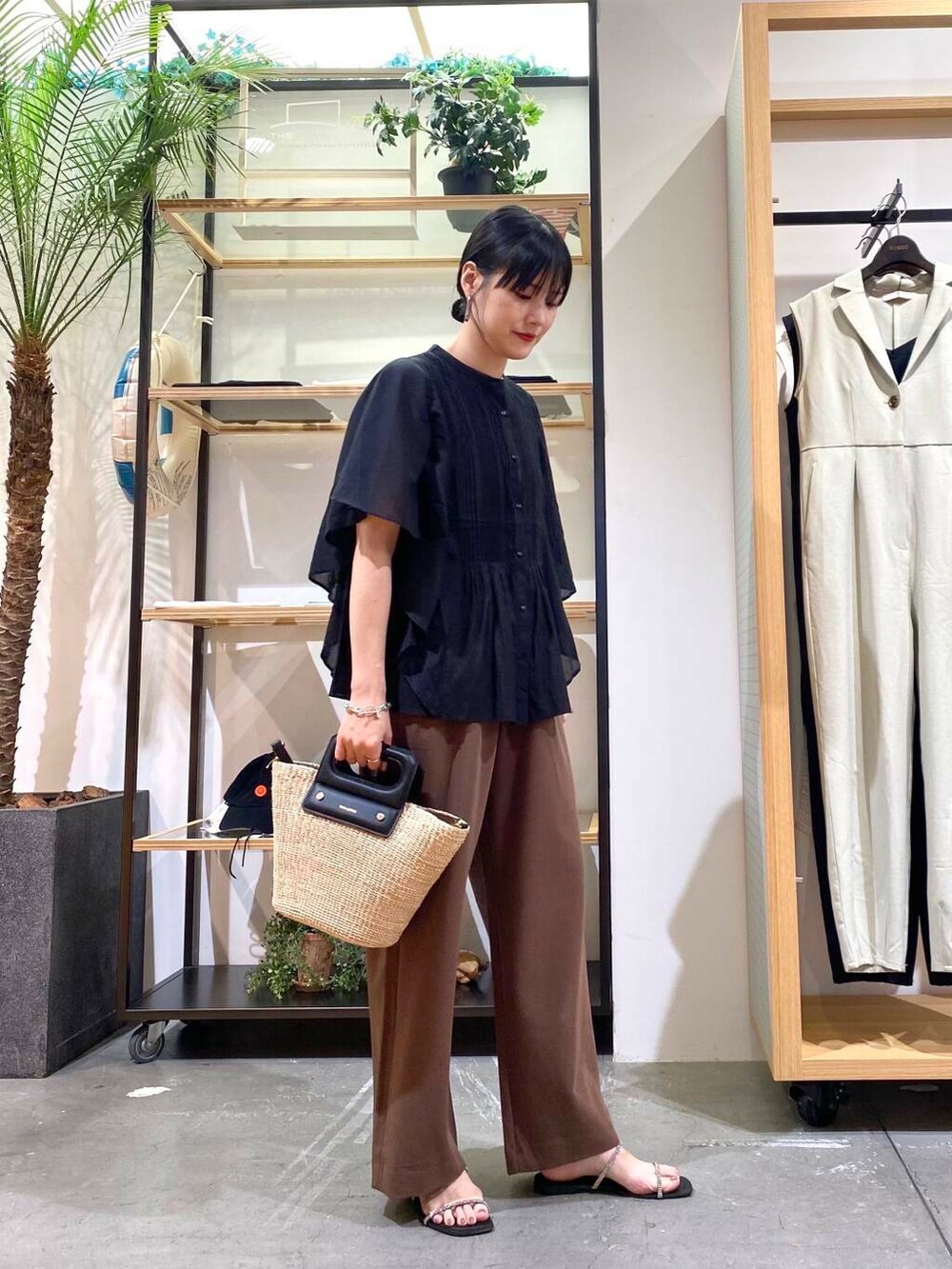 ベージュ系のハンドバッグ、ブラック系のサンダル、ブラック系のシャツ/ブラウスを着用したレディースの夏コーディネートの2枚目の写真