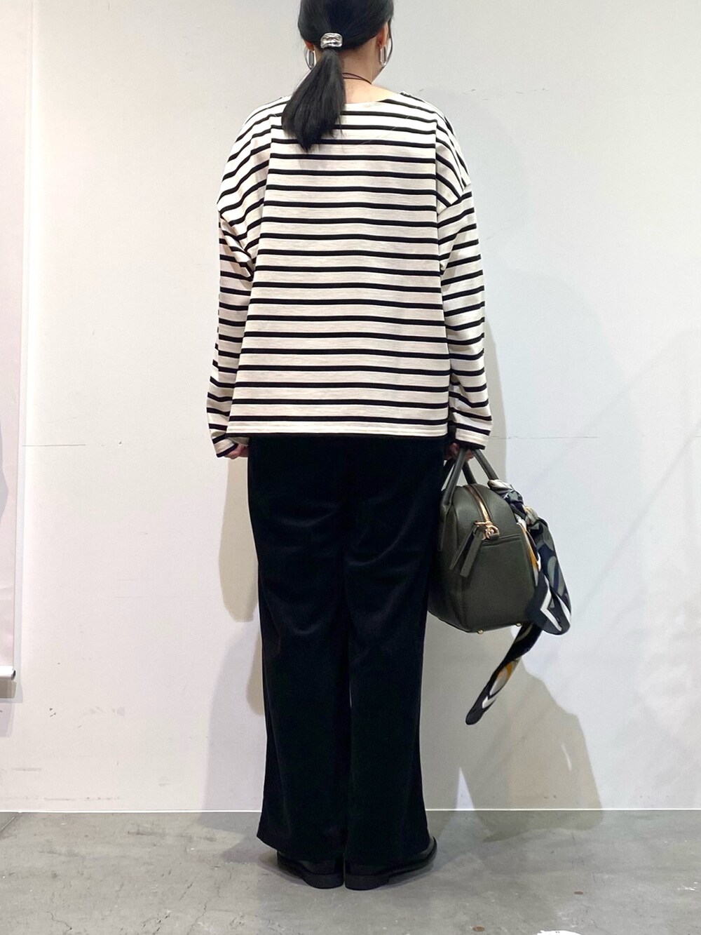 ホワイト系のTシャツ/カットソー、ブラック系のその他パンツ、グリーン系のボストンバッグを着用したレディースの秋コーディネートの6枚目の写真