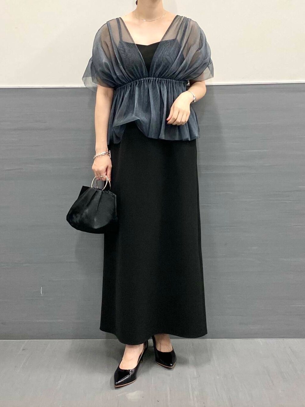 ブラック系のパンプス、ブラック系のハンドバッグ、ブラック系のワンピースを着用したレディースの秋コーディネートの5枚目の写真