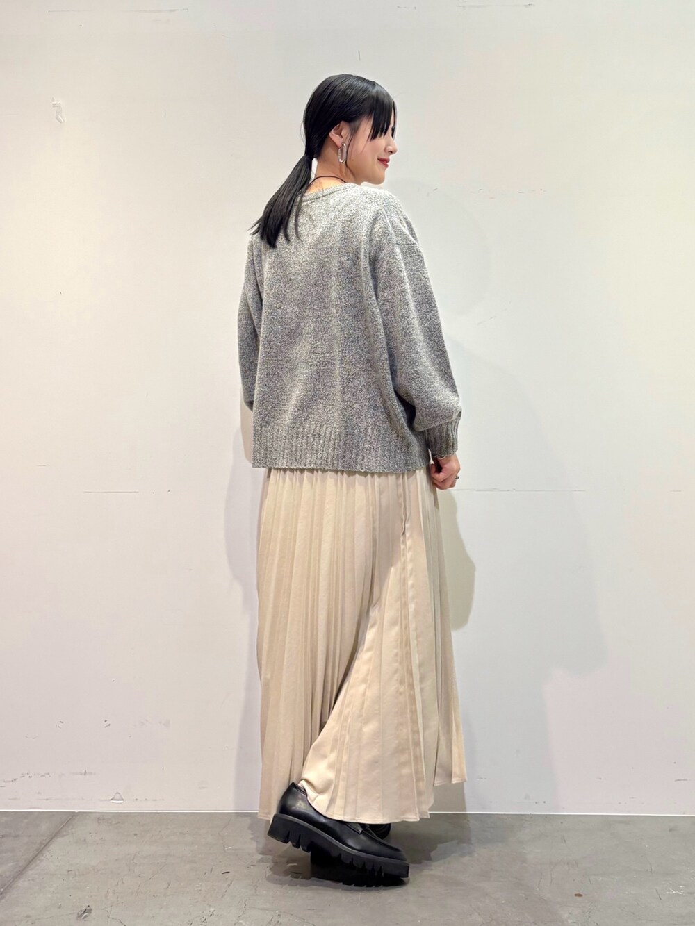 グレー系のニット/セーター、ホワイト系のスカート、ブラック系のローファーを着用したレディースの冬コーディネートの3枚目の写真