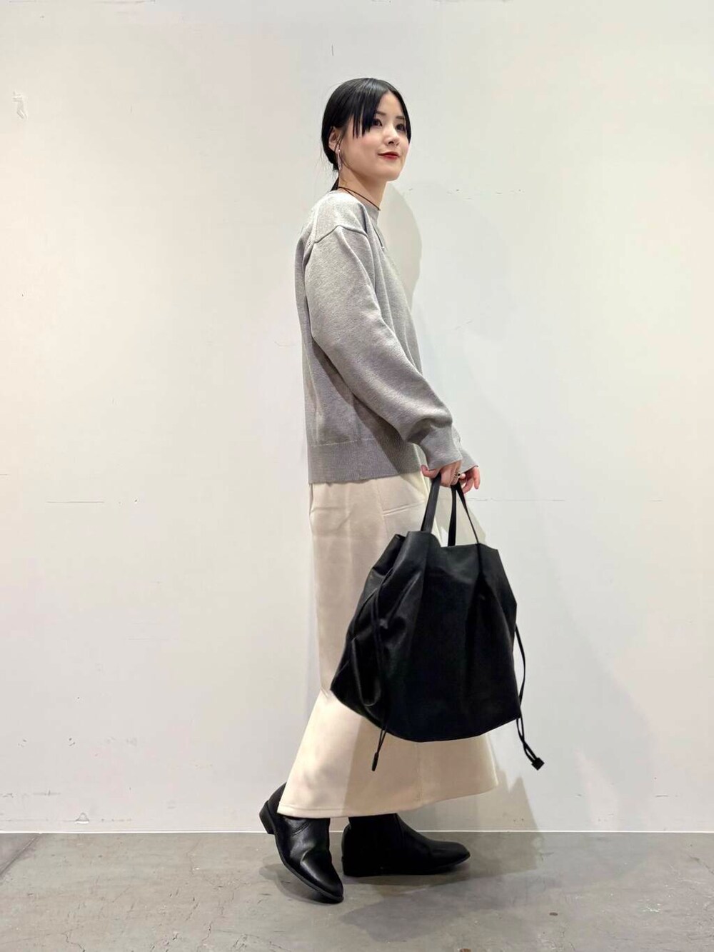 ブラック系のトートバッグ、ブラック系のブーツ、ホワイト系のスカートを着用したレディースの冬コーディネートの2枚目の写真