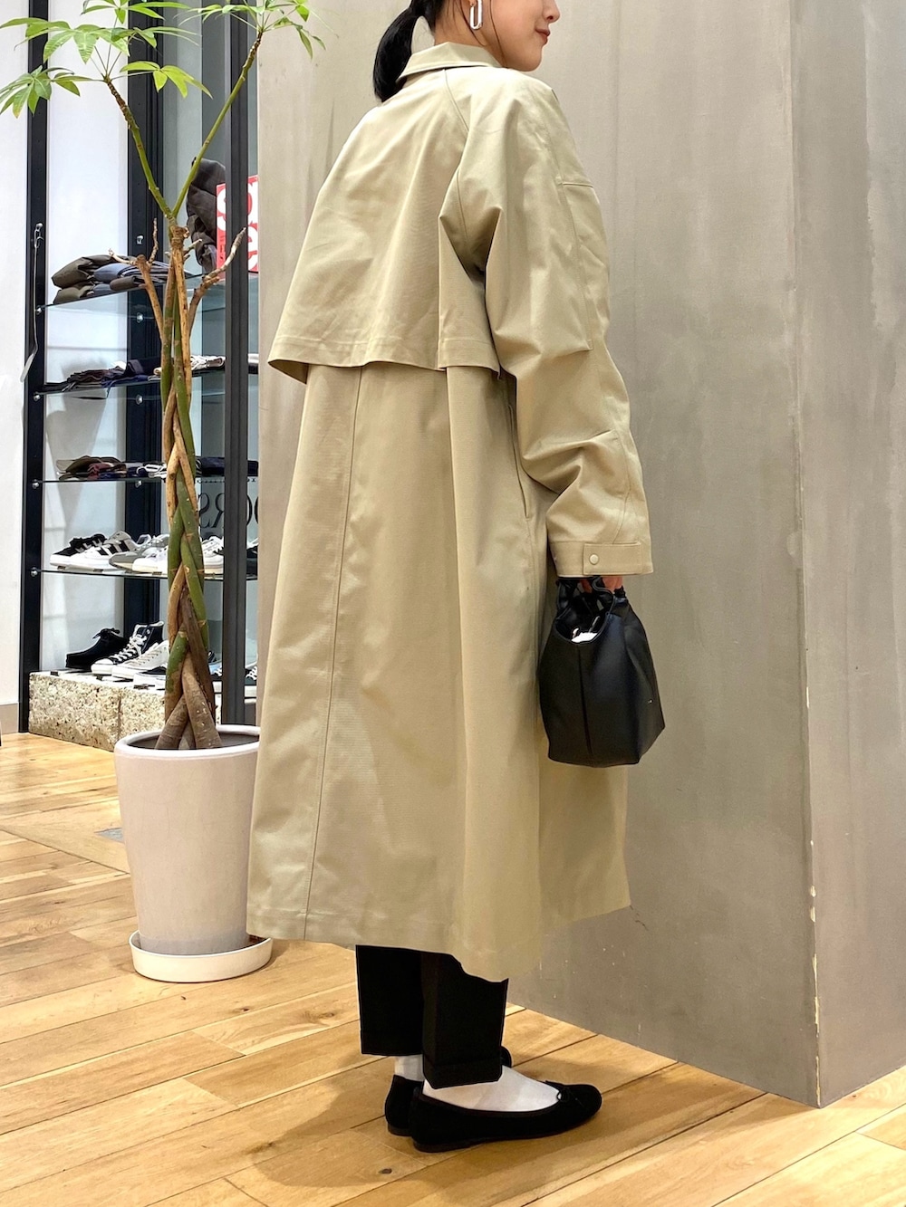 グリーン系のステンカラーコート、ホワイト系のニット/セーター、ブラック系のその他パンツを着用したレディースの冬コーディネートの4枚目の写真