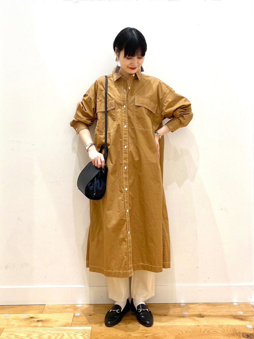 イエロー系のワンピース、ベージュ系のデニムパンツ、ブラック系のショルダーバッグを着用したレディースの春コーディネートの3枚目の写真