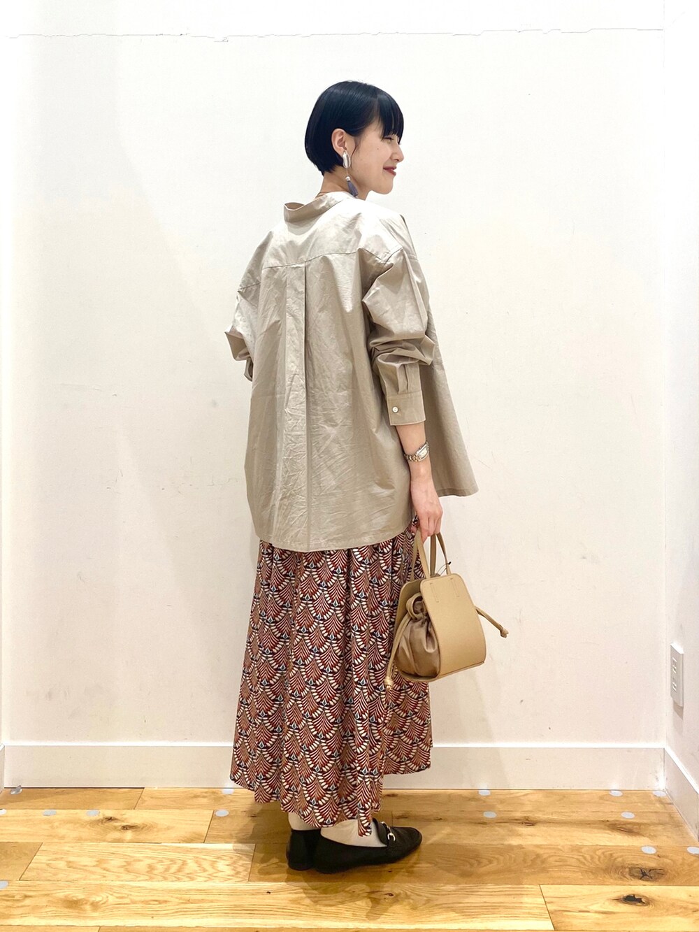 ベージュ系のシャツ/ブラウス、ホワイト系のタンクトップ、オレンジ系のスカートを着用したレディースの春コーディネートの2枚目の写真