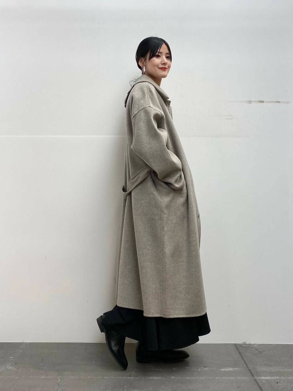 レッド系のニット/セーター、ブラック系のブーツ、ブラック系のスカートを着用したレディースの秋コーディネートの2枚目の写真