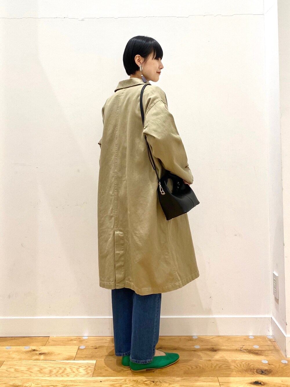 ベージュ系のステンカラーコート、ホワイト系のTシャツ/カットソー、ブルー系のデニムパンツを着用したレディースの春コーディネートの2枚目の写真