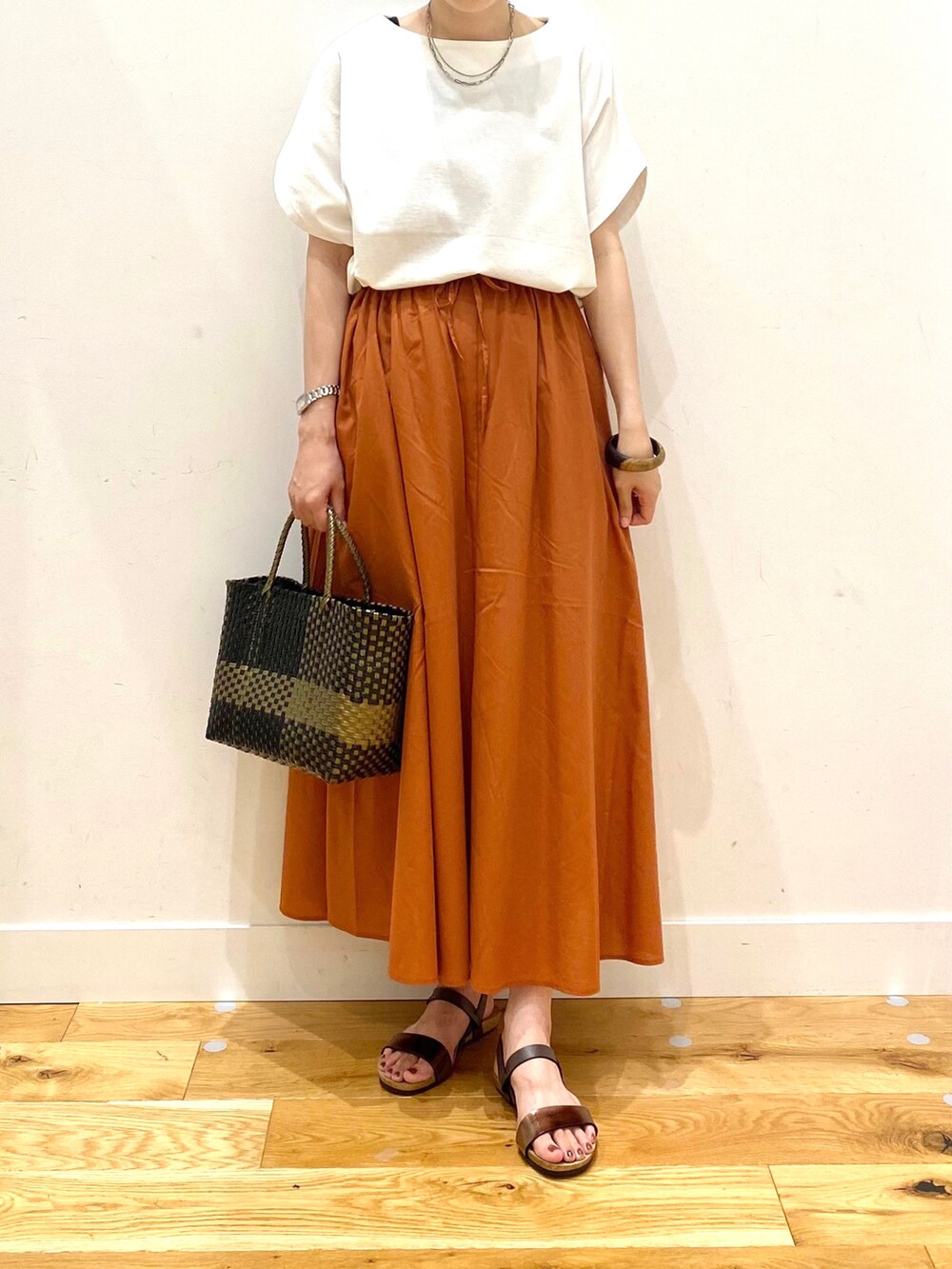 ホワイト系のTシャツ/カットソー、オレンジ系のスカート、ブラック系のトートバッグを着用したレディースの夏コーディネートの4枚目の写真
