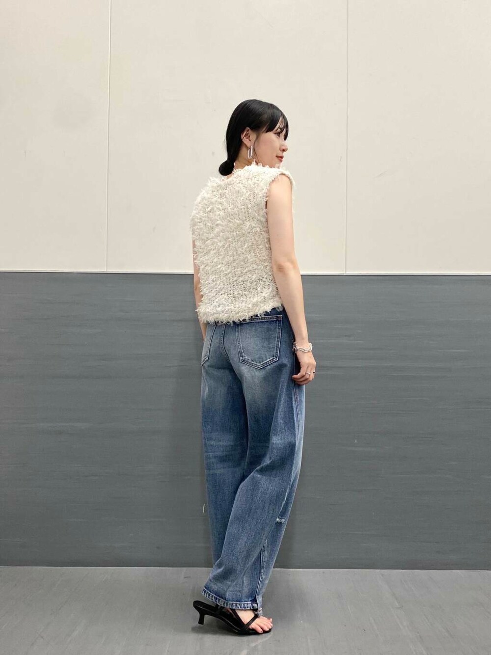 ブルー系のデニムパンツ、ホワイト系のベスト、ブラック系のサンダルを着用したレディースの夏コーディネートの4枚目の写真