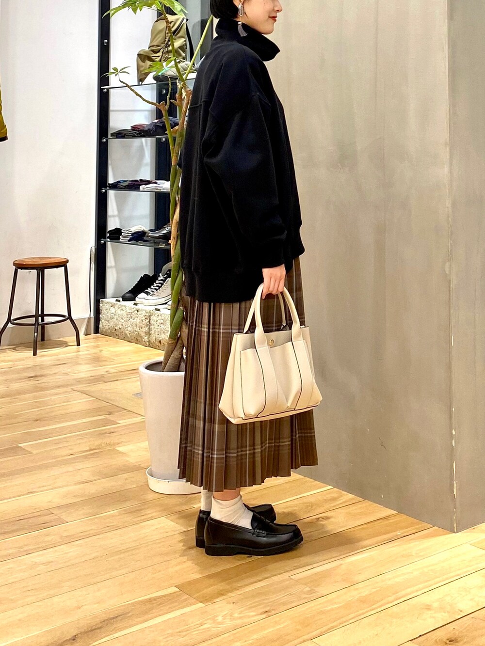 ブラック系のスウェット、ブラウン系のスカート、ホワイト系のトートバッグを着用したレディースの冬コーディネートの5枚目の写真