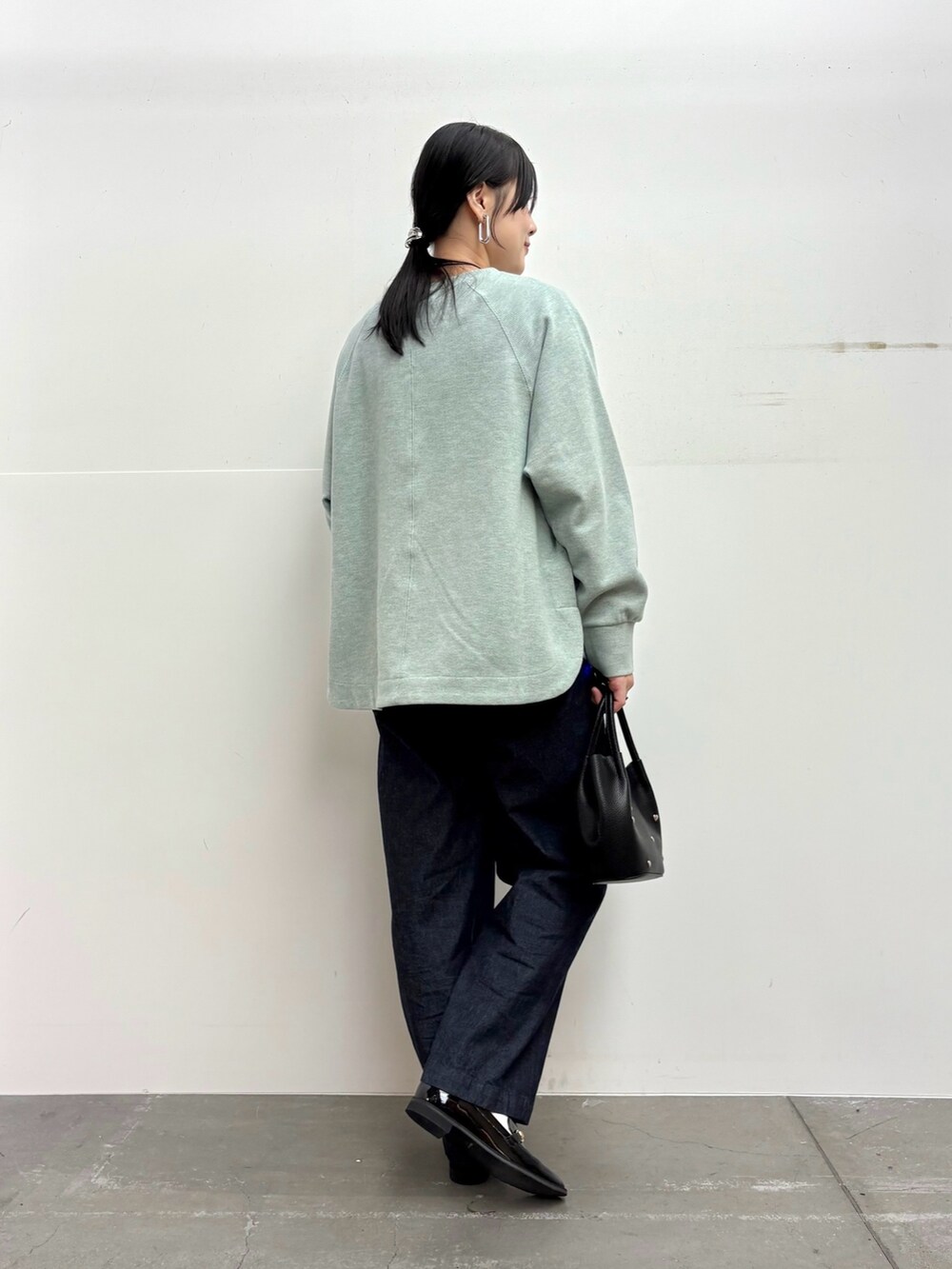 グリーン系のTシャツ/カットソー、ブルー系のデニムパンツ、ブラック系のショルダーバッグを着用したレディースの冬コーディネートの4枚目の写真