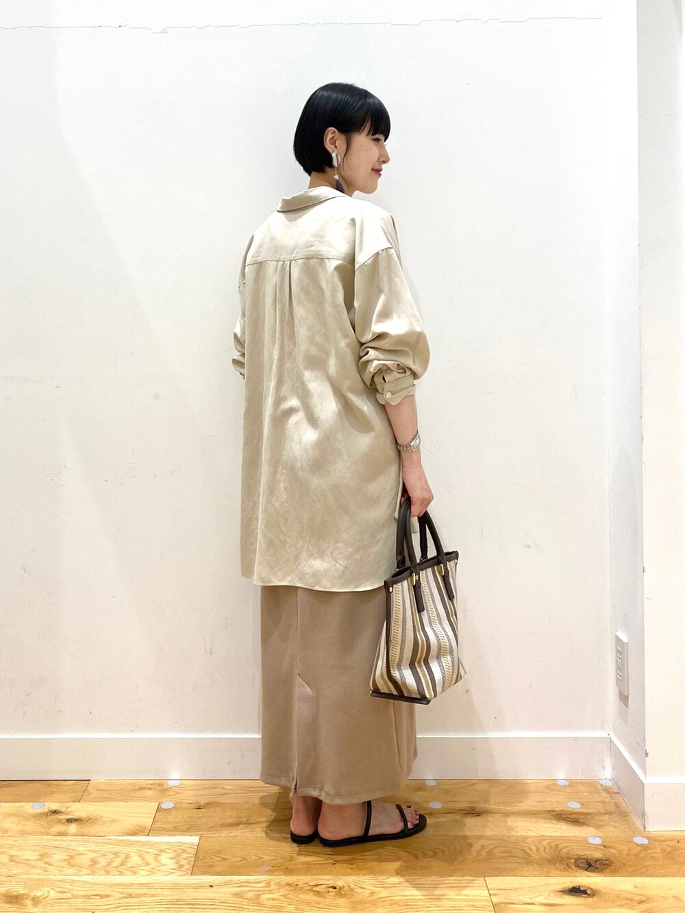 ベージュ系のシャツ/ブラウス、ホワイト系のタンクトップ、ベージュ系のスカートを着用したレディースの春コーディネートの3枚目の写真