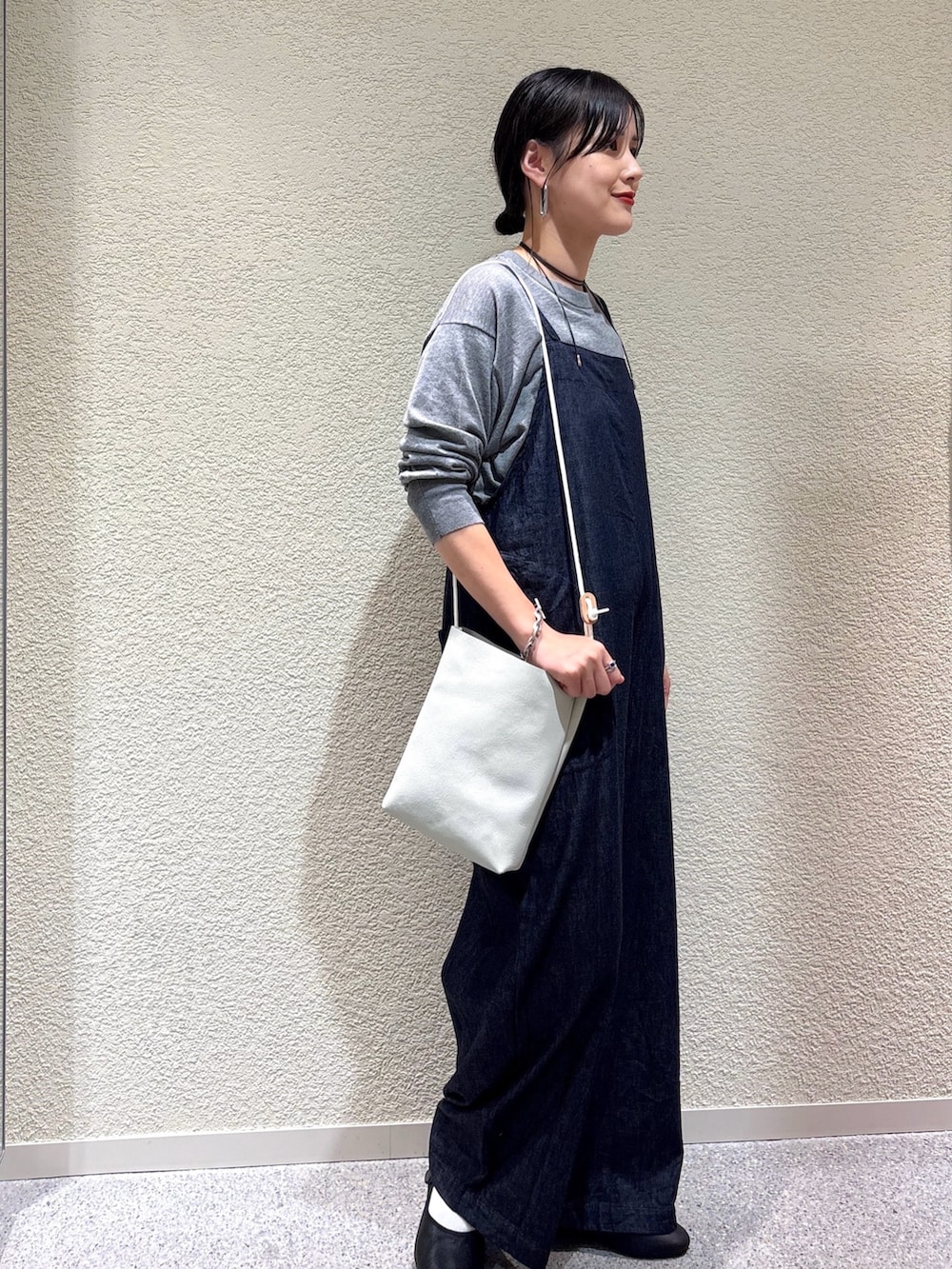 グレー系のニット/セーター、ブルー系のサロペット/オーバーオール、ホワイト系のショルダーバッグを着用したレディースの秋コーディネートの2枚目の写真