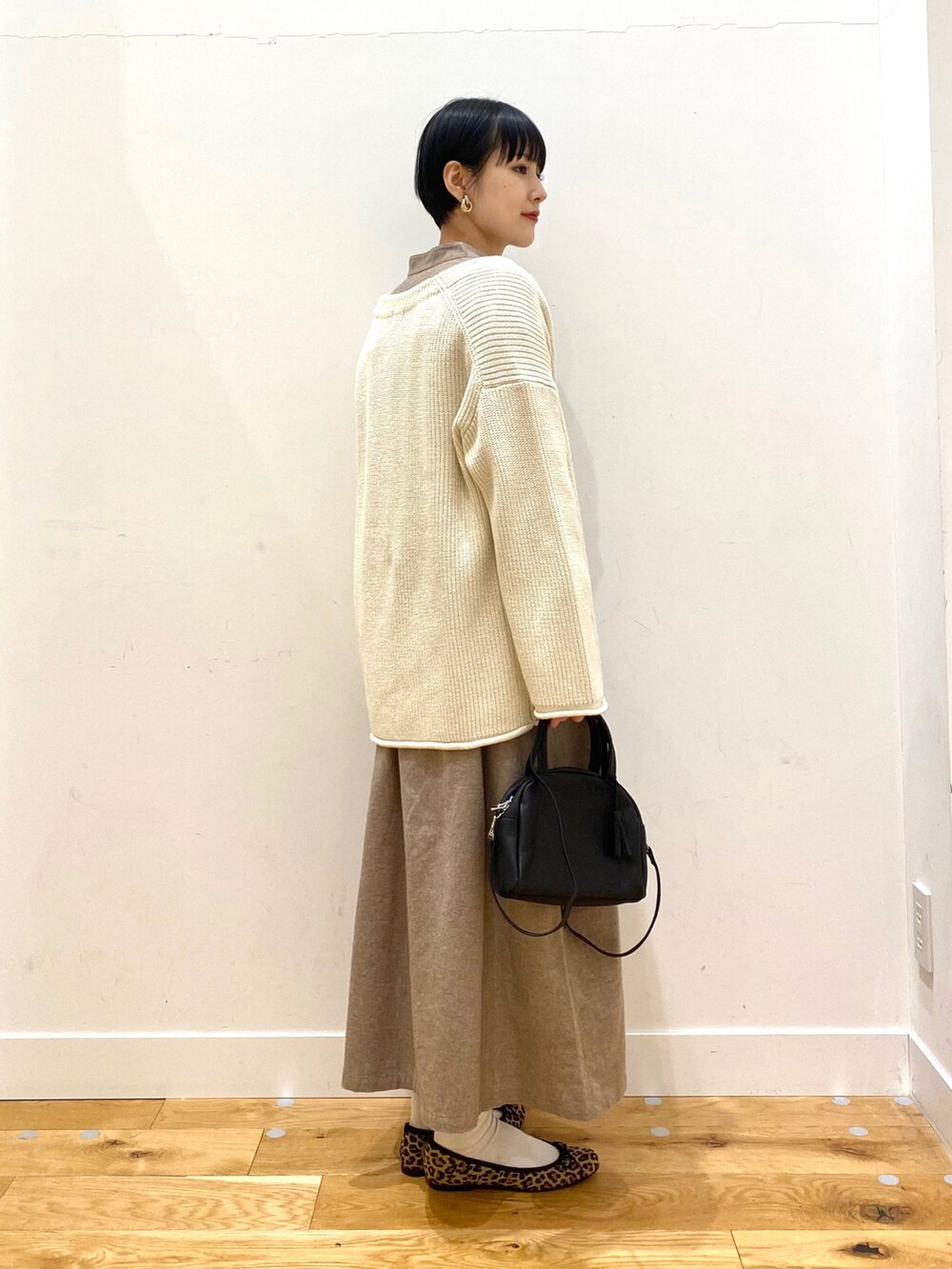 ホワイト系のカーディガン/ボレロ、ベージュ系のワンピース、ブラック系のボストンバッグを着用したレディースの冬コーディネートの2枚目の写真