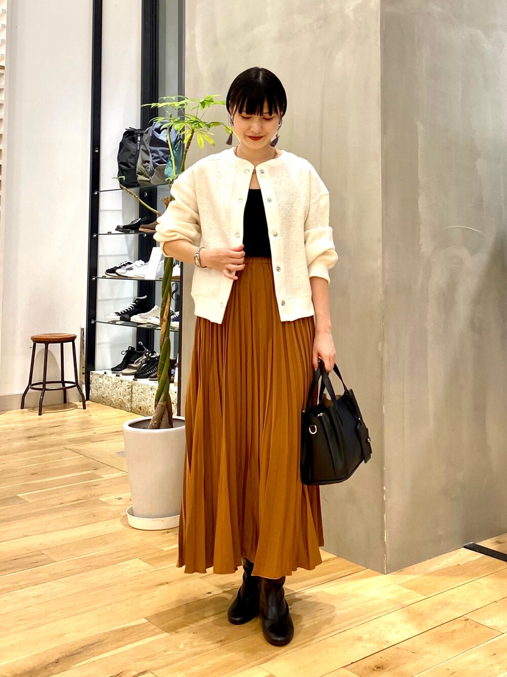 ホワイト系のカーディガン/ボレロ、ブラック系のタンクトップ、イエロー系のスカートを着用したレディースの秋コーディネートの2枚目の写真