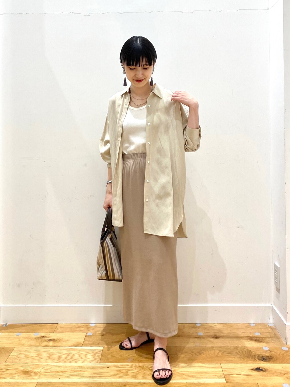 ベージュ系のシャツ/ブラウス、ホワイト系のタンクトップ、ベージュ系のスカートを着用したレディースの春コーディネートの2枚目の写真