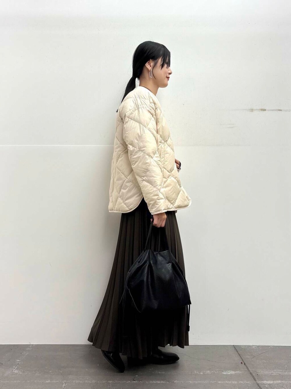 ブラック系のショルダーバッグ、ホワイト系のダウンジャケット/コート、ブラック系のブーツを着用したレディースの冬コーディネートの2枚目の写真