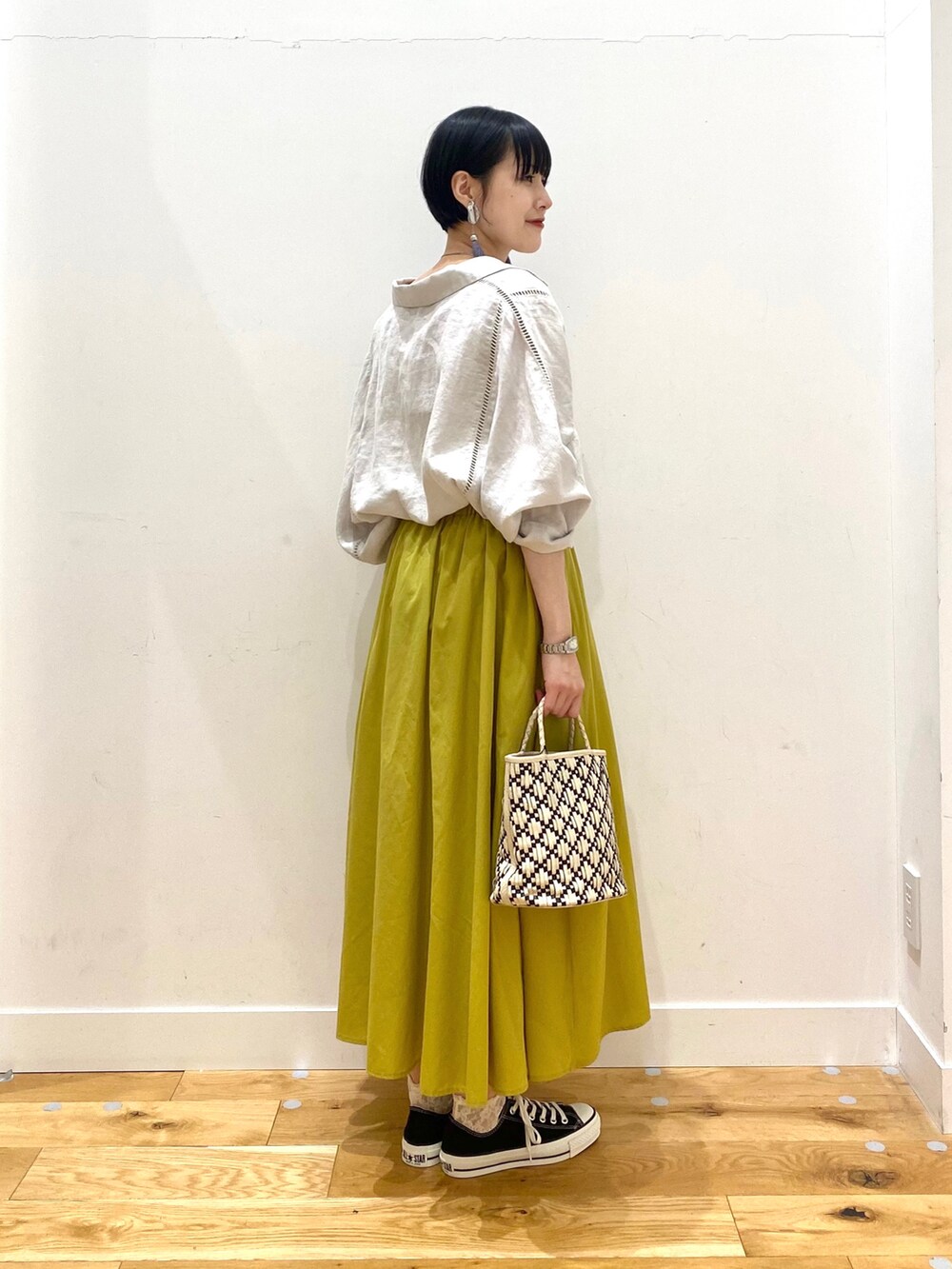 ベージュ系のシャツ/ブラウス、イエロー系のスカート、ブラック系のスニーカーを着用したレディースの春コーディネートの3枚目の写真