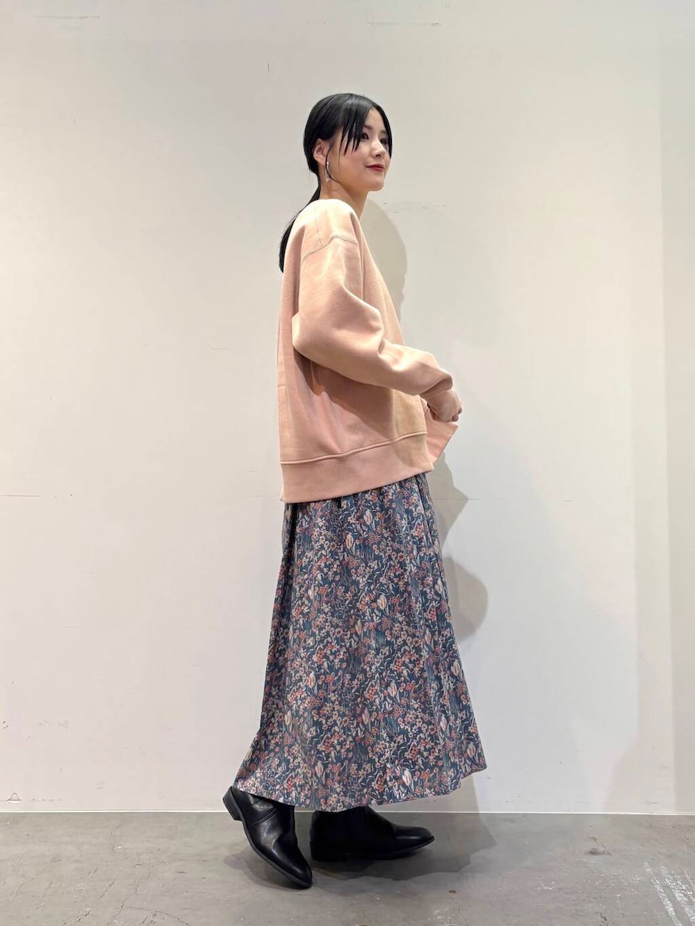 ブラック系のブーツ、ブルー系のスカート、ピンク系のスウェットを着用したレディースの冬コーディネートの2枚目の写真