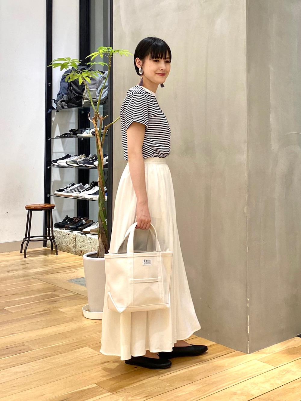 グレー系のカーディガン/ボレロ、ホワイト系のスカート、ホワイト系のトートバッグを着用したレディースの春コーディネートの4枚目の写真