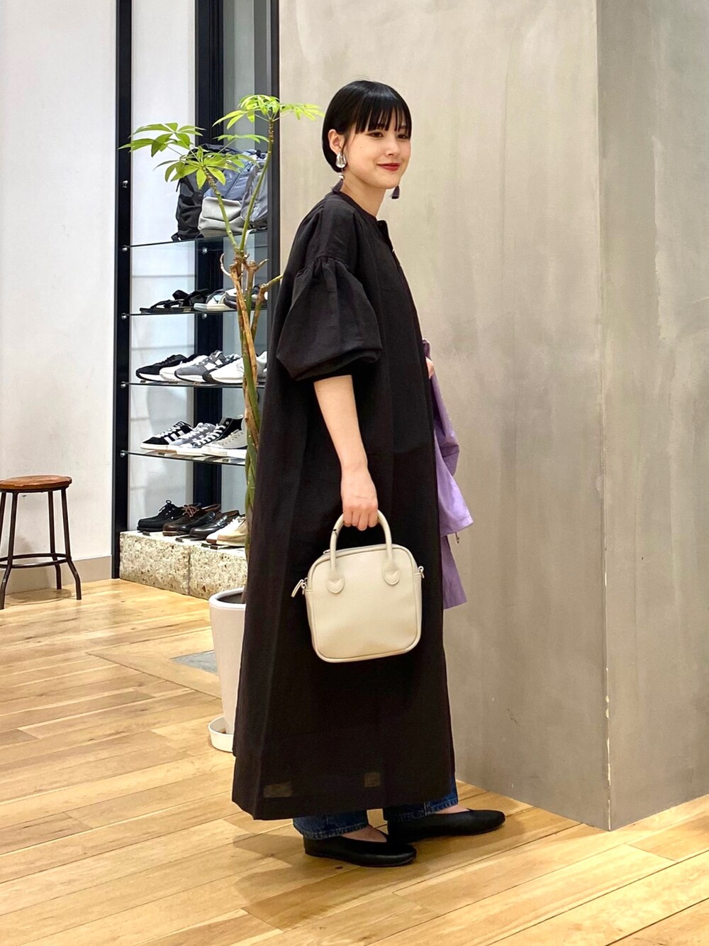 パープル系のブルゾン、ブルー系のデニムパンツ、ベージュ系のショルダーバッグを着用したレディースの春コーディネートの2枚目の写真