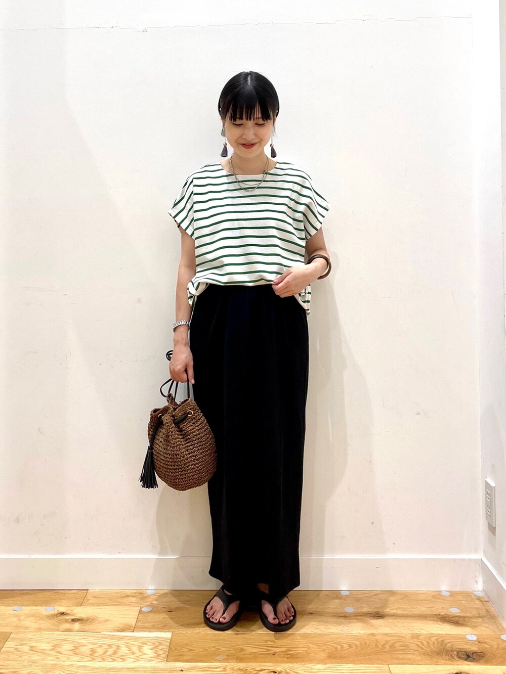 グリーン系のTシャツ/カットソー、ブラック系のスカート、ブラウン系のショルダーバッグを着用したレディースの夏コーディネートの2枚目の写真