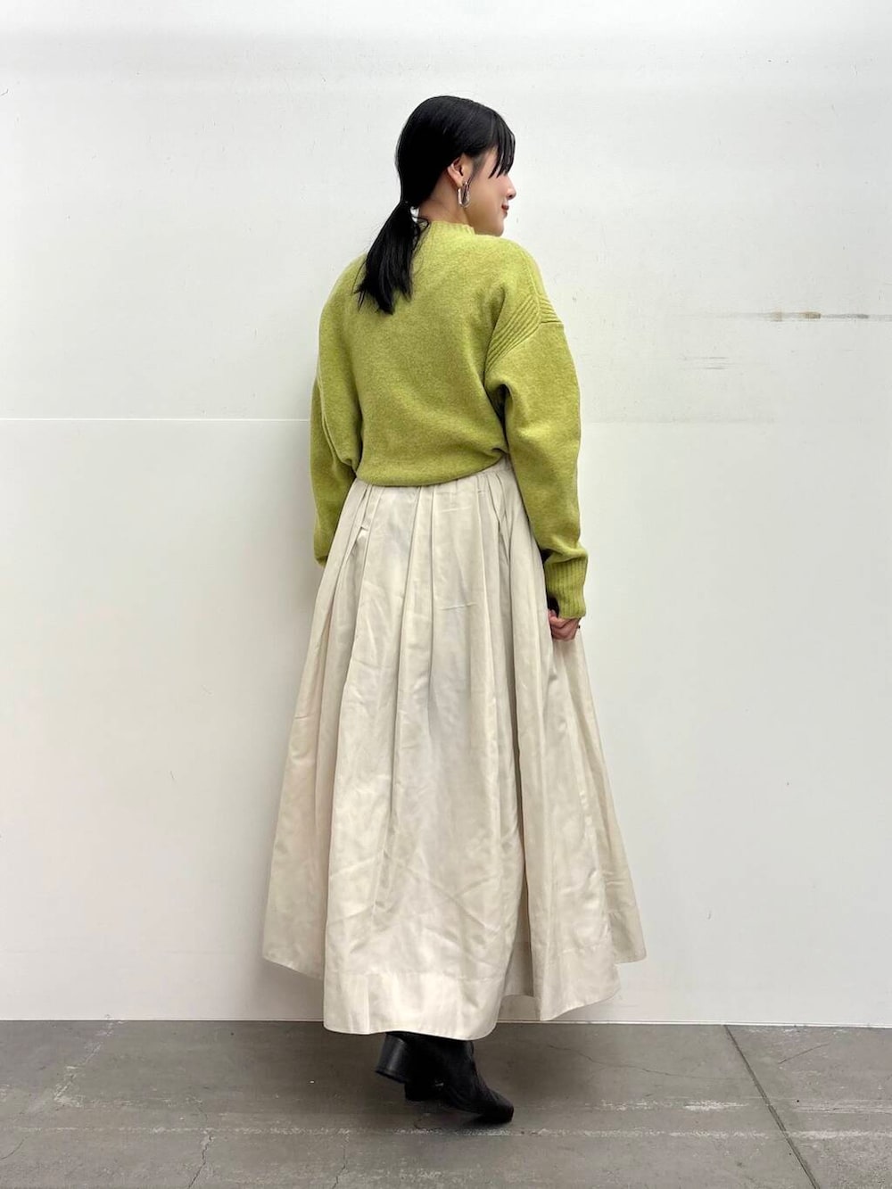 ブラック系のブーツ、ホワイト系のスカート、グリーン系のニット/セーターを着用したレディースの冬コーディネートの3枚目の写真