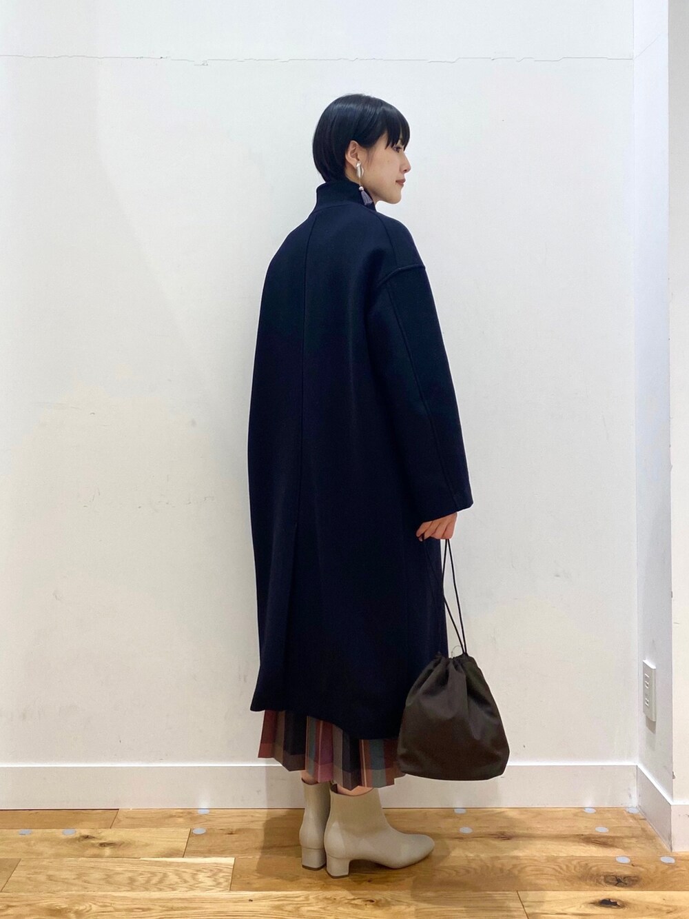 ブルー系のチェスターコート、ブラウン系のニット/セーター、パープル系のスカートを着用したレディースの秋コーディネートの3枚目の写真