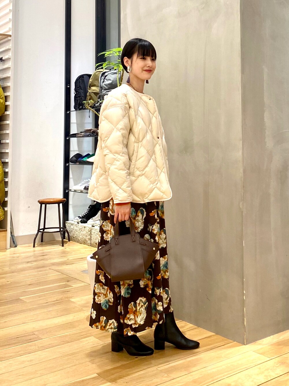 ベージュ系のダウンジャケット/コート、オレンジ系のニット/セーター、ブラウン系のスカートを着用したレディースの秋コーディネートの2枚目の写真