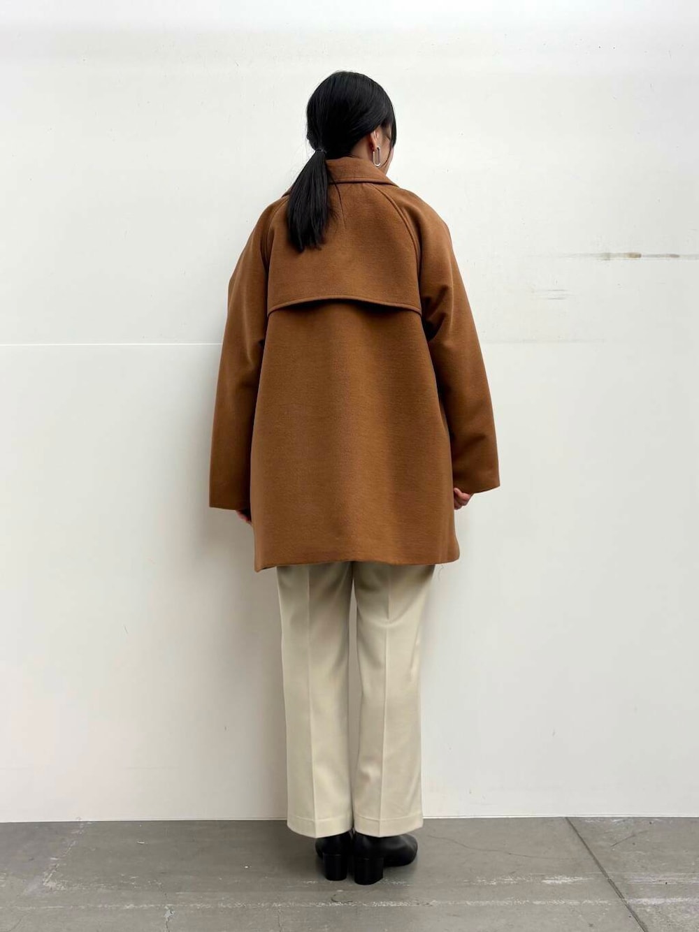 ブラック系のブーツ、イエロー系のステンカラーコート、ホワイト系のその他パンツを着用したレディースの冬コーディネートの3枚目の写真