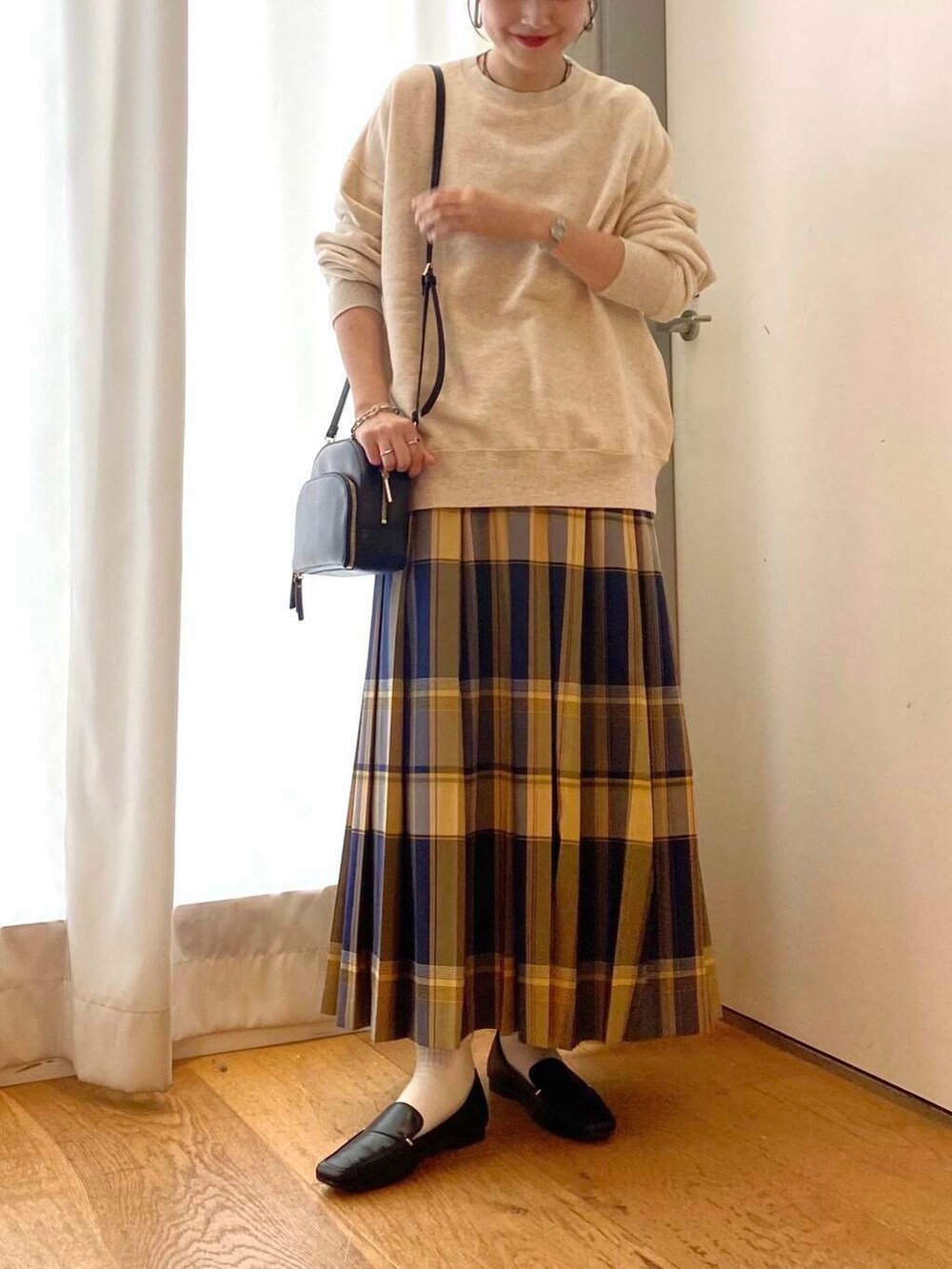 ブラック系のローファー、ブラック系のショルダーバッグ、ブルー系のスカートを着用したレディースの秋コーディネートの5枚目の写真