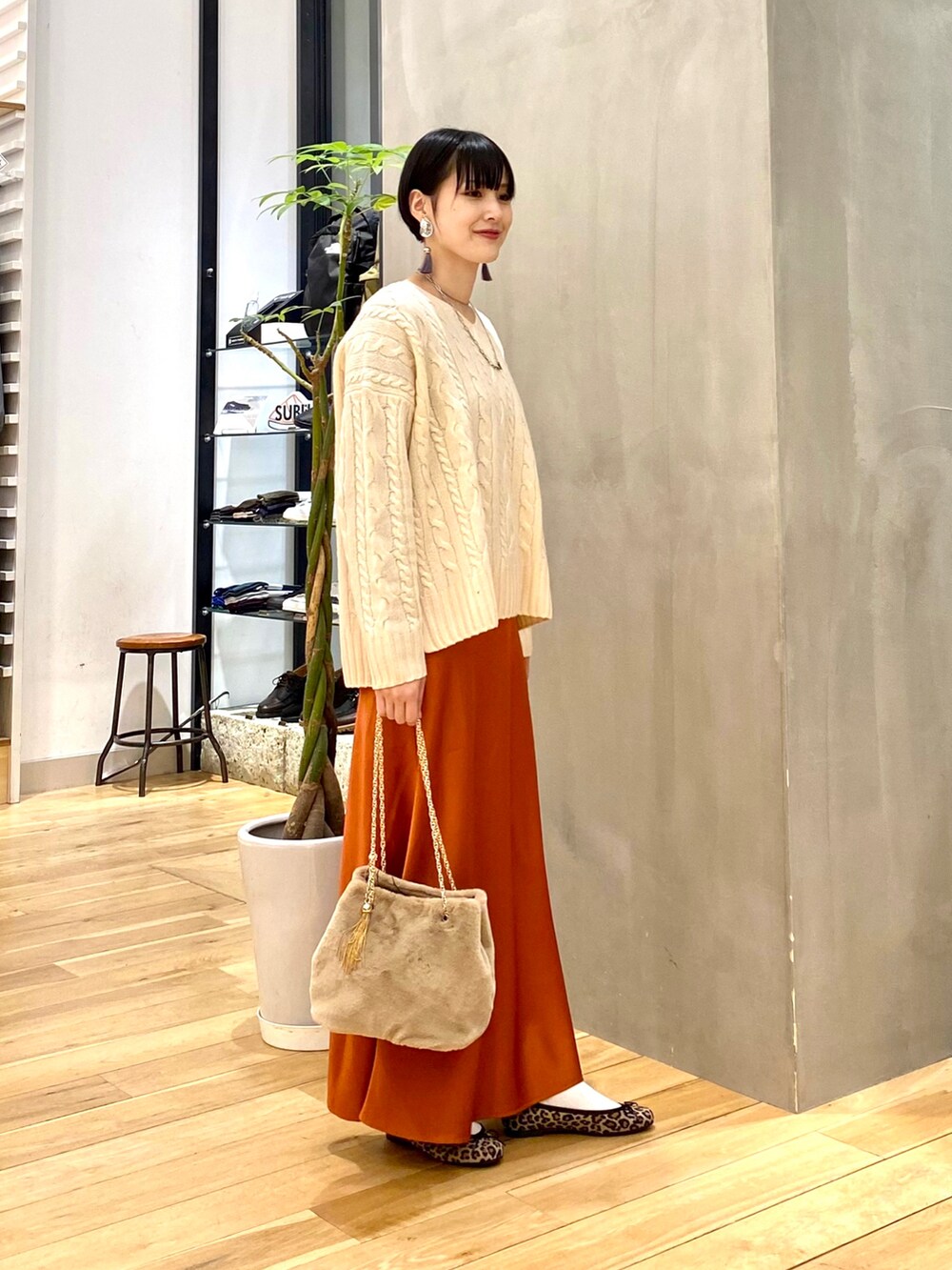 ホワイト系のダウンジャケット/コート、ホワイト系のニット/セーター、オレンジ系のスカートを着用したレディースの冬コーディネートの4枚目の写真