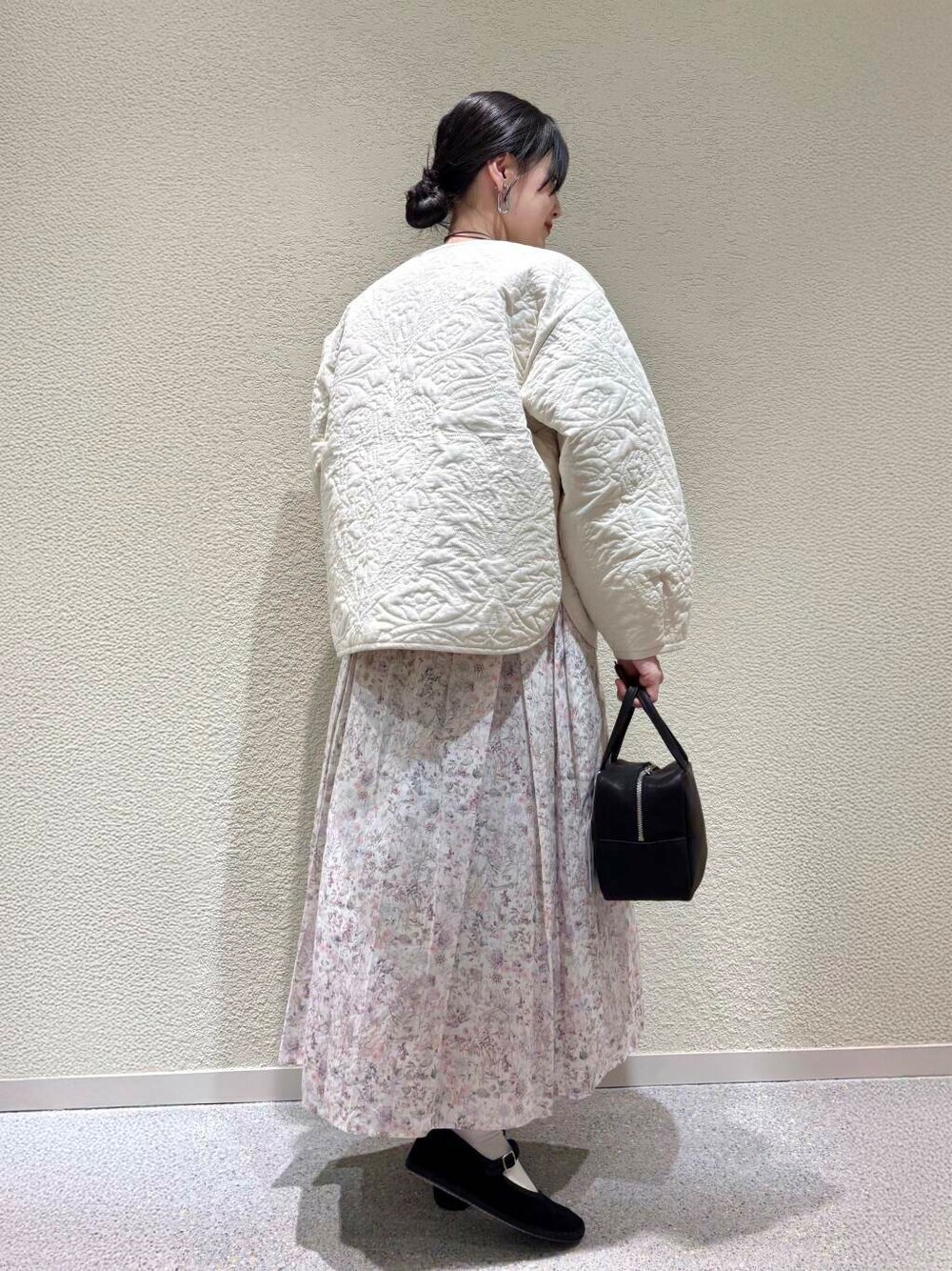 ベージュ系のTシャツ/カットソー、ホワイト系のスカート、ホワイト系のダウンジャケット/コートを着用したレディースの春コーディネートの3枚目の写真