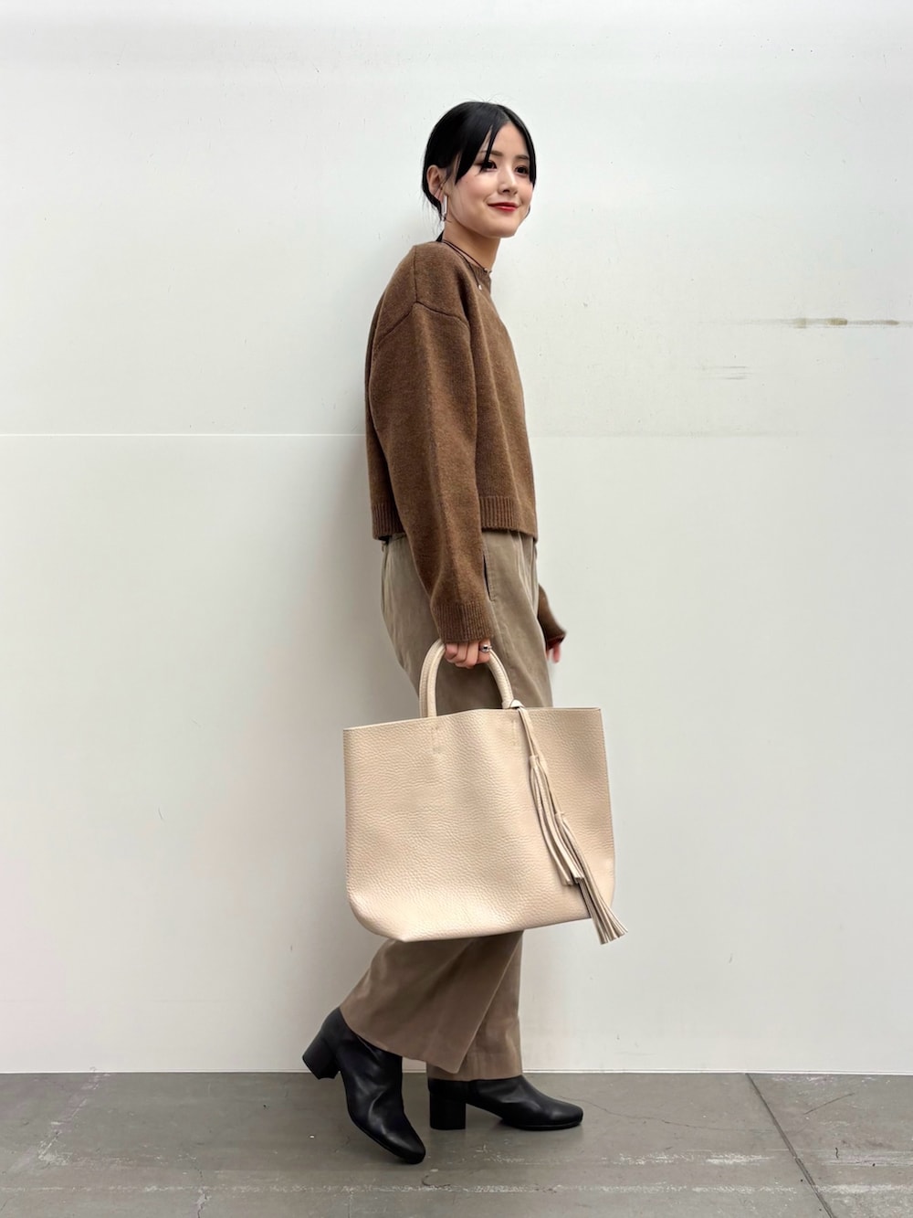 ブラウン系のニット/セーター、ベージュ系のその他パンツ、ホワイト系のトートバッグを着用したレディースの冬コーディネートの2枚目の写真