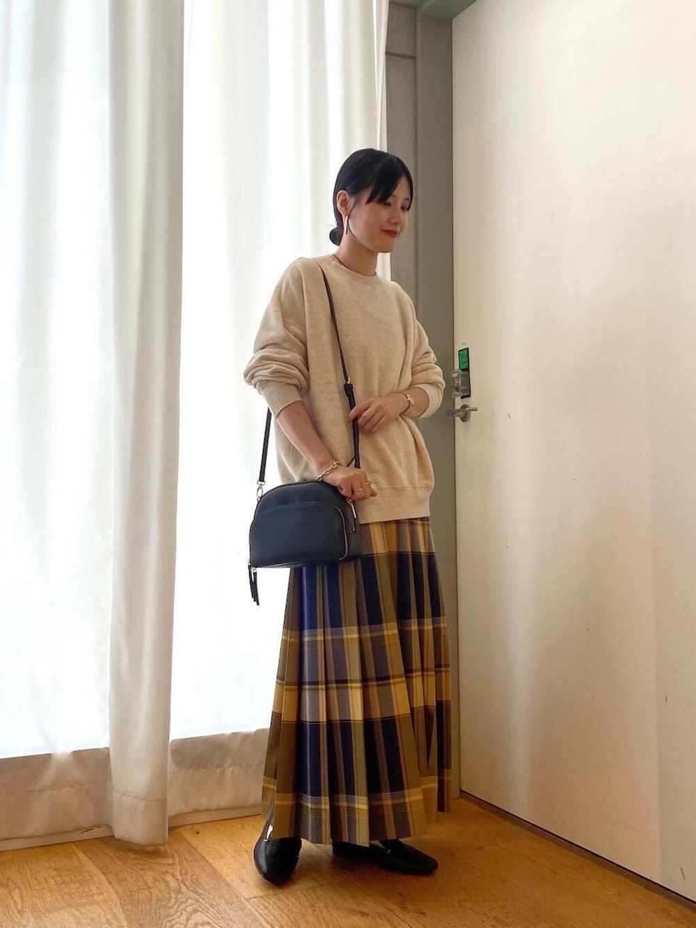 ブラック系のローファー、ブラック系のショルダーバッグ、ブルー系のスカートを着用したレディースの秋コーディネートの2枚目の写真