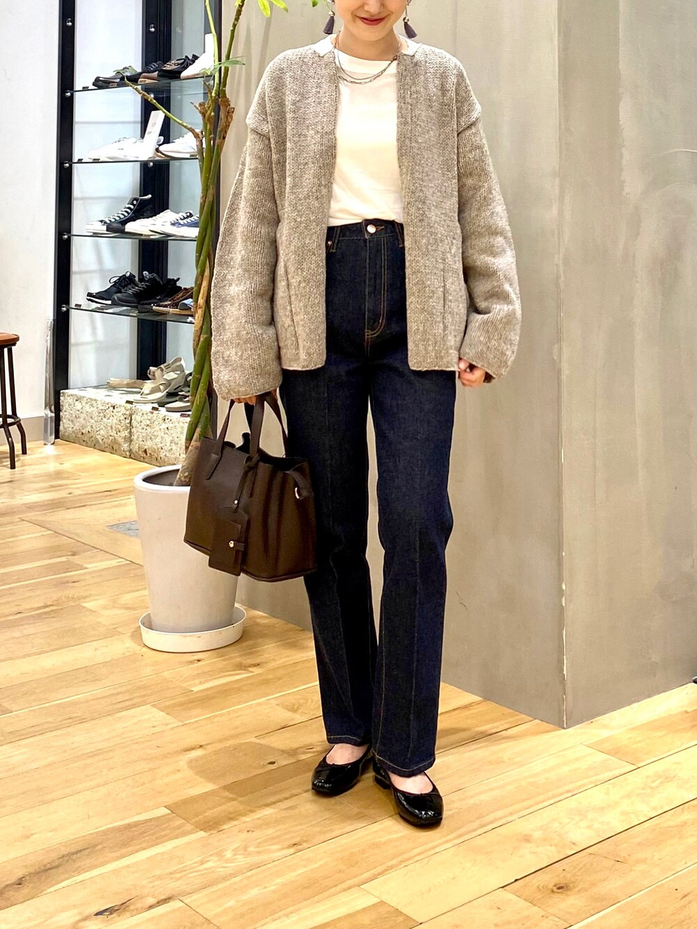 グレー系のカーディガン/ボレロ、ホワイト系のTシャツ/カットソー、ブルー系のデニムパンツを着用したレディースの秋コーディネートの4枚目の写真