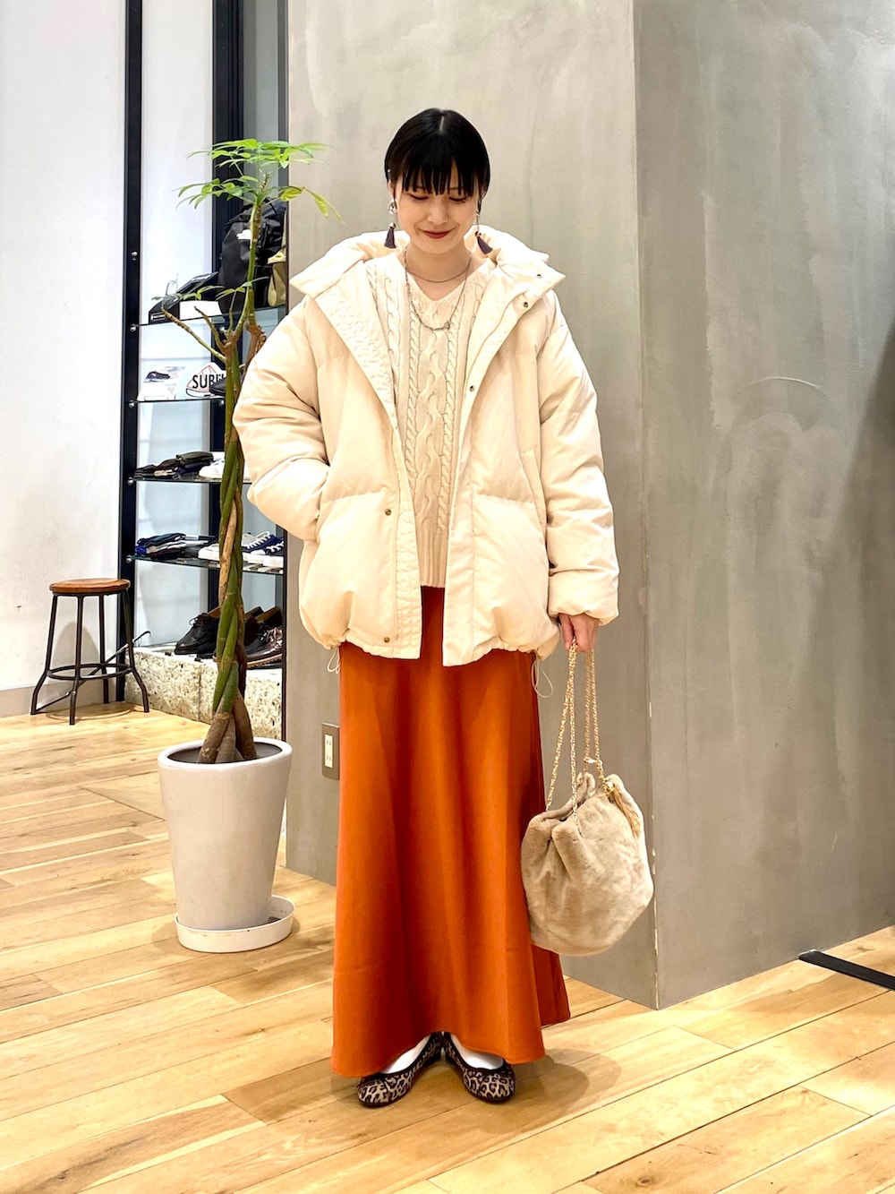 ホワイト系のダウンジャケット/コート、ホワイト系のニット/セーター、オレンジ系のスカートを着用したレディースの冬コーディネートの2枚目の写真