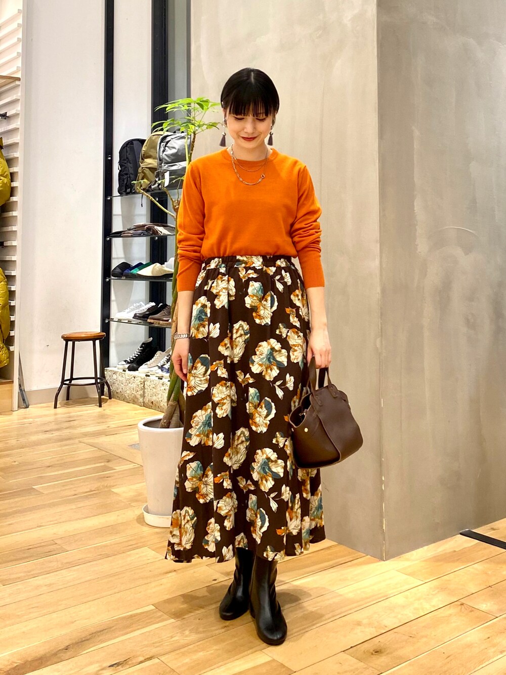 ベージュ系のダウンジャケット/コート、オレンジ系のニット/セーター、ブラウン系のスカートを着用したレディースの秋コーディネートの3枚目の写真
