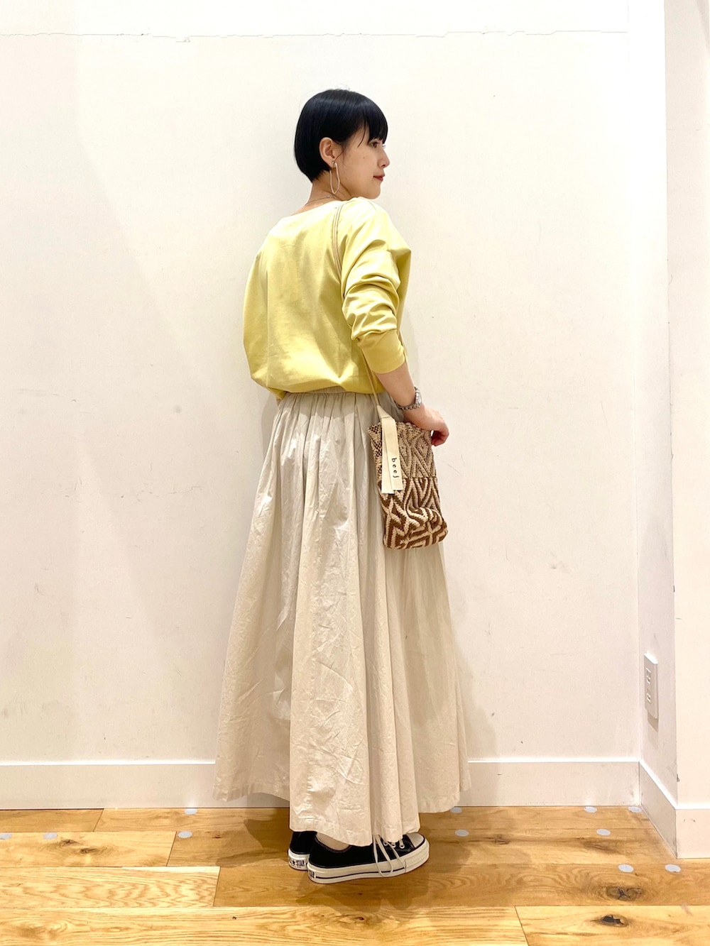 イエロー系のTシャツ/カットソー、ホワイト系のスカート、ブラウン系のショルダーバッグを着用したレディースの春コーディネートの3枚目の写真