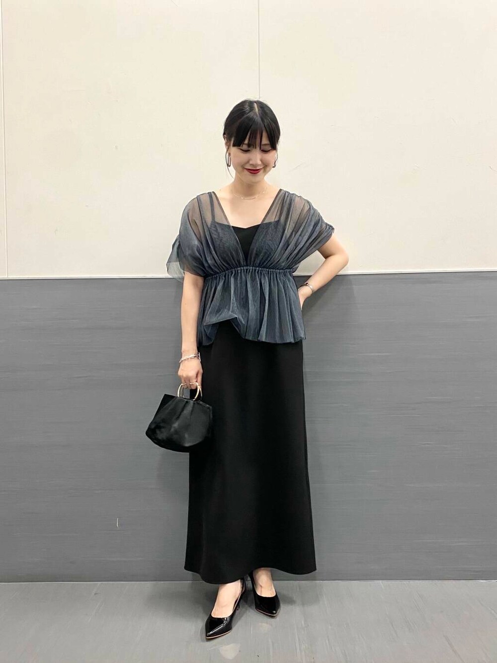 ブラック系のパンプス、ブラック系のハンドバッグ、ブラック系のワンピースを着用したレディースの秋コーディネートの2枚目の写真