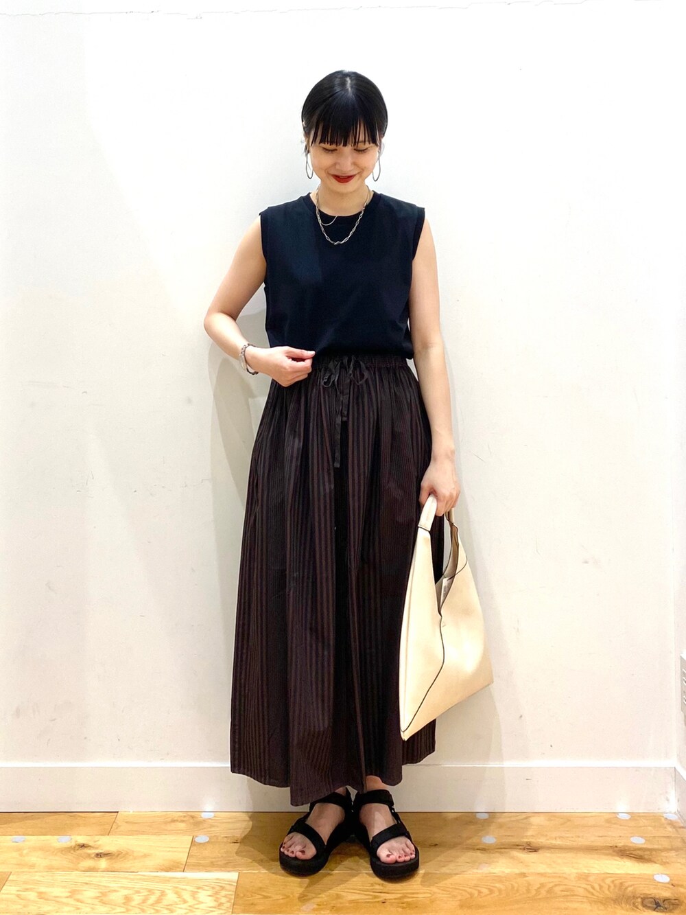 ブラック系のTシャツ/カットソー、ブラウン系のスカート、ホワイト系のトートバッグを着用したレディースの春コーディネートの2枚目の写真