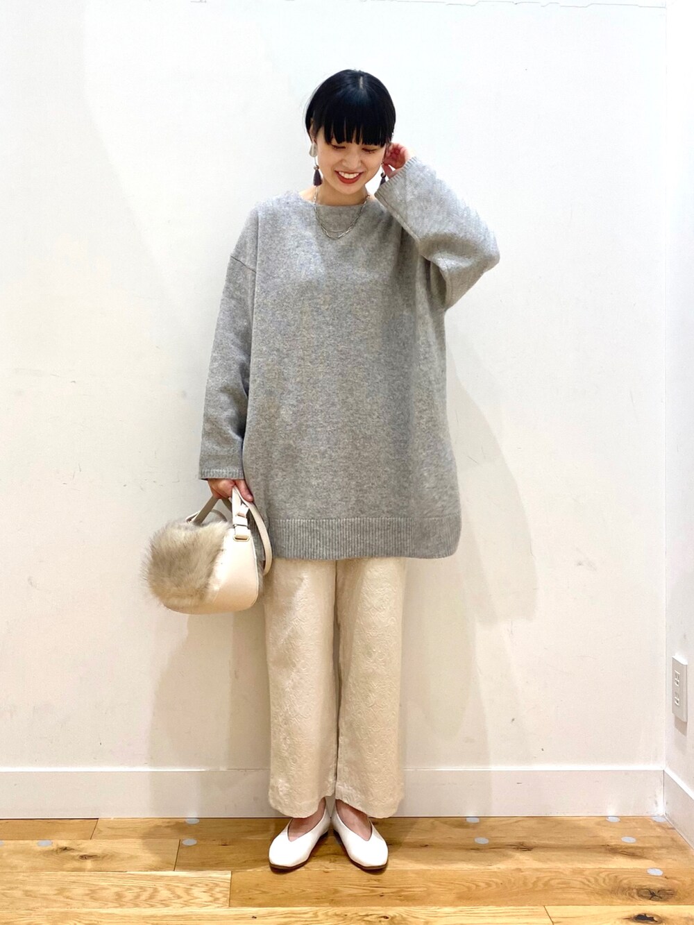 ブルー系のチェスターコート、グレー系のニット/セーター、ホワイト系のその他パンツを着用したレディースの冬コーディネートの4枚目の写真